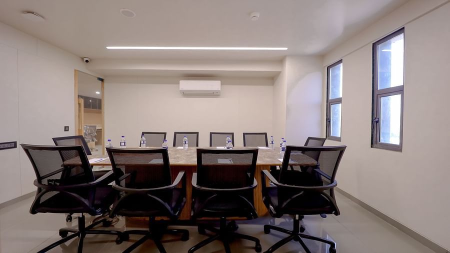 An image of a conference hall at Pride Resort Ambaji featuring some chairs and a centre table 